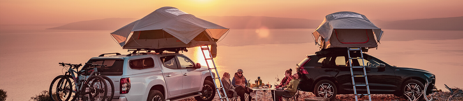 Two couples with yakima roof tents in front of a sea back drop