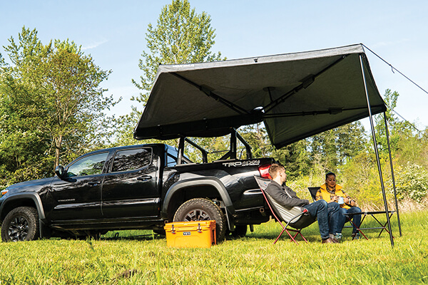 A couple sit under a huge Yakima awning attached to their black pickup