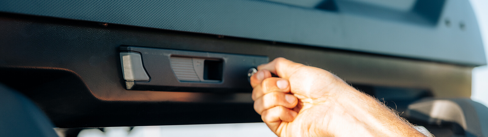 A man closes the lock on his Thule roof box