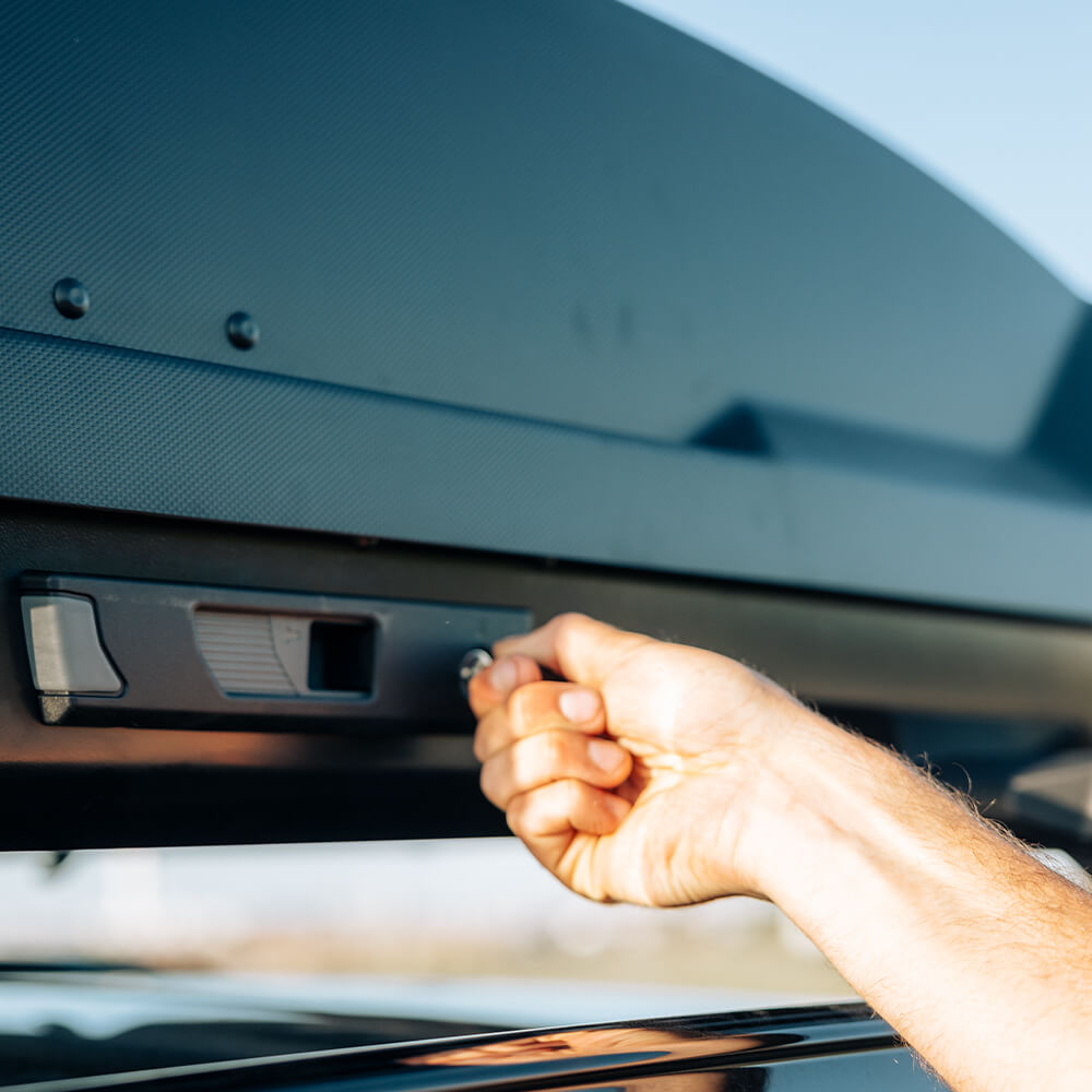 A man closes the lock on his Thule roof box