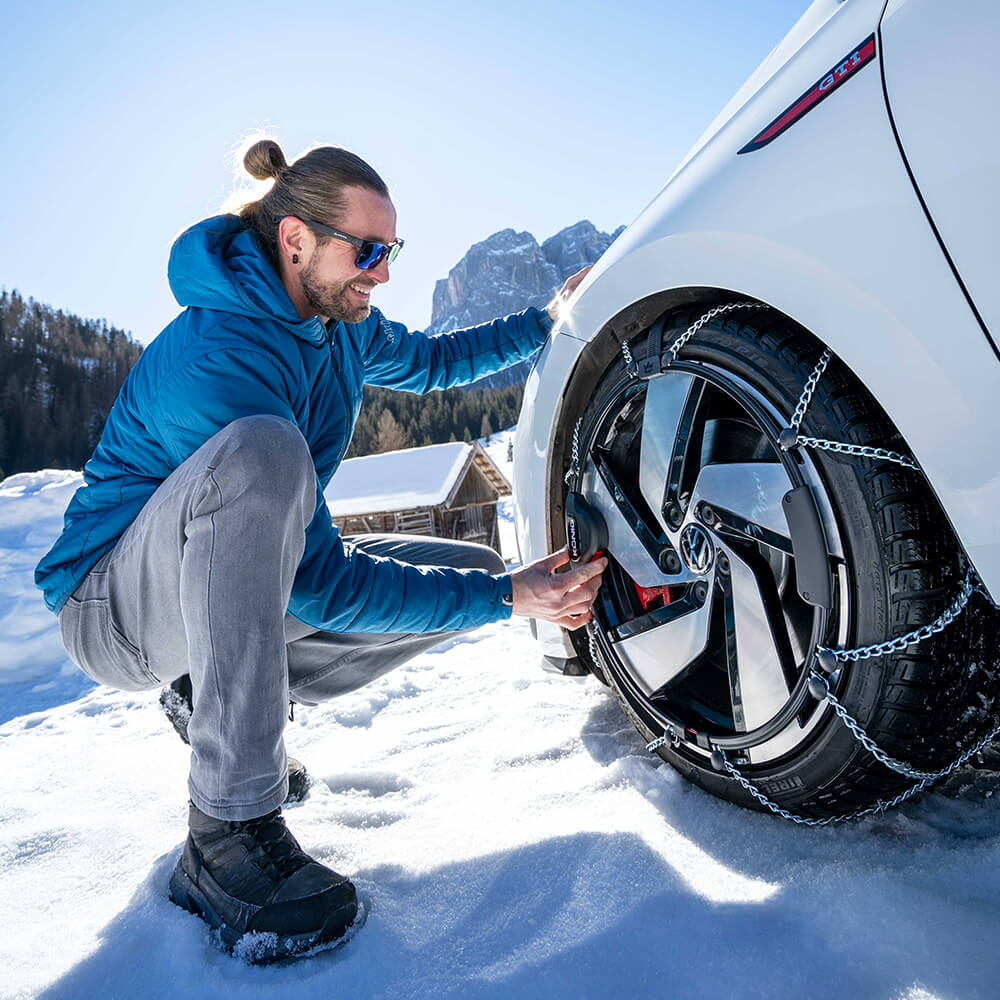A man takes a 'selfie' in a mountain location with his car fitted with Konig snow chains