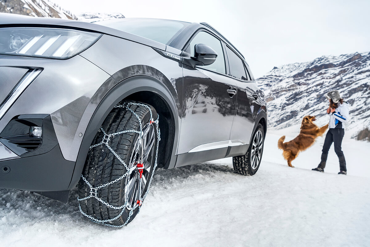 A König XG-Cross Snow Chain fitted to a Peugeot car on a snow covered road
