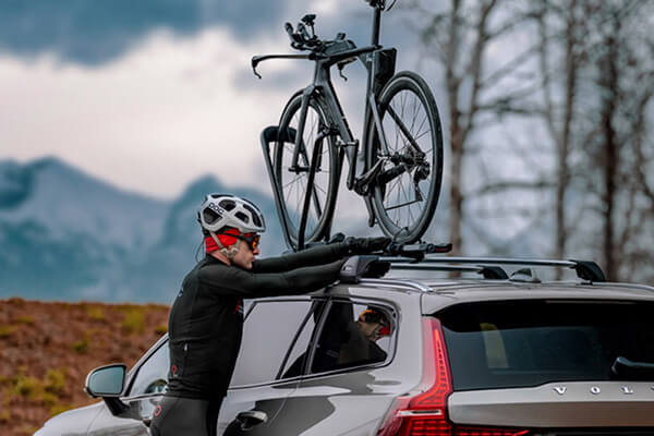 Man secures his TT bike into a Yakima roof mounting bike carrier