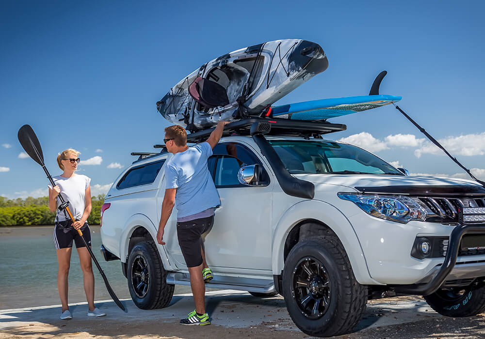 A couple ready to unload a kayak and a SUP from their pickup