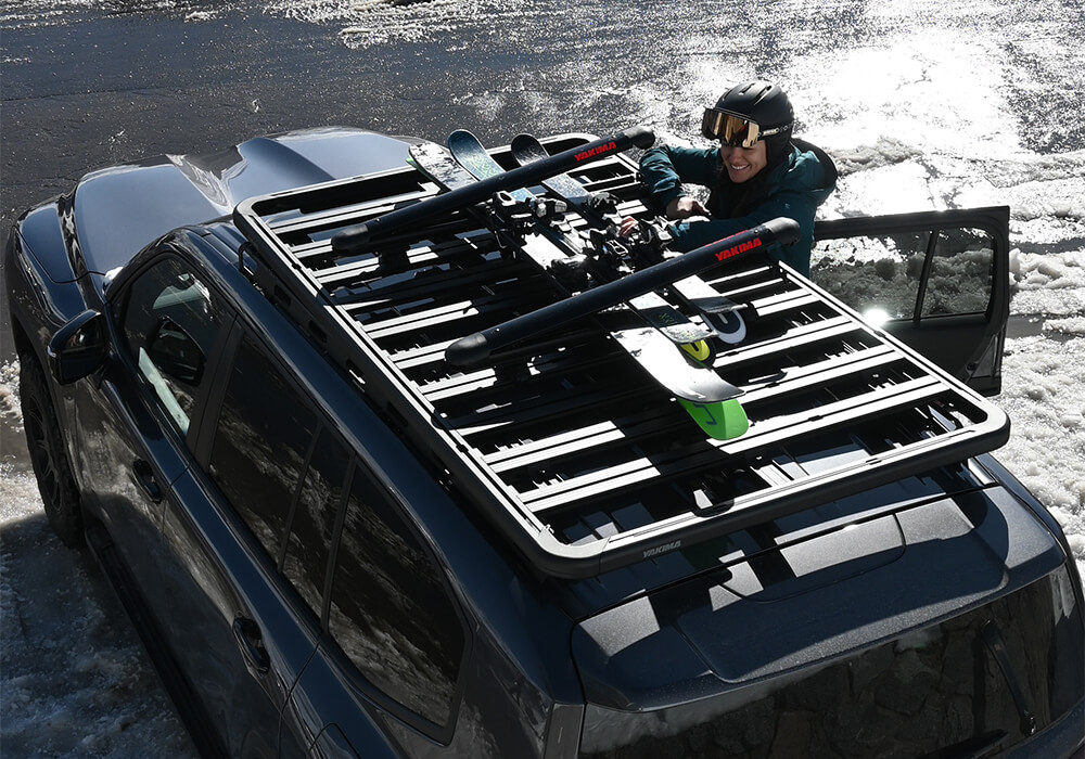 A woman unloading skis from a Yakima FatCat Ski Carrier