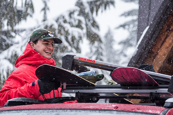 Man loading two snowboards into a Yakima Ski / Snowboard carrier